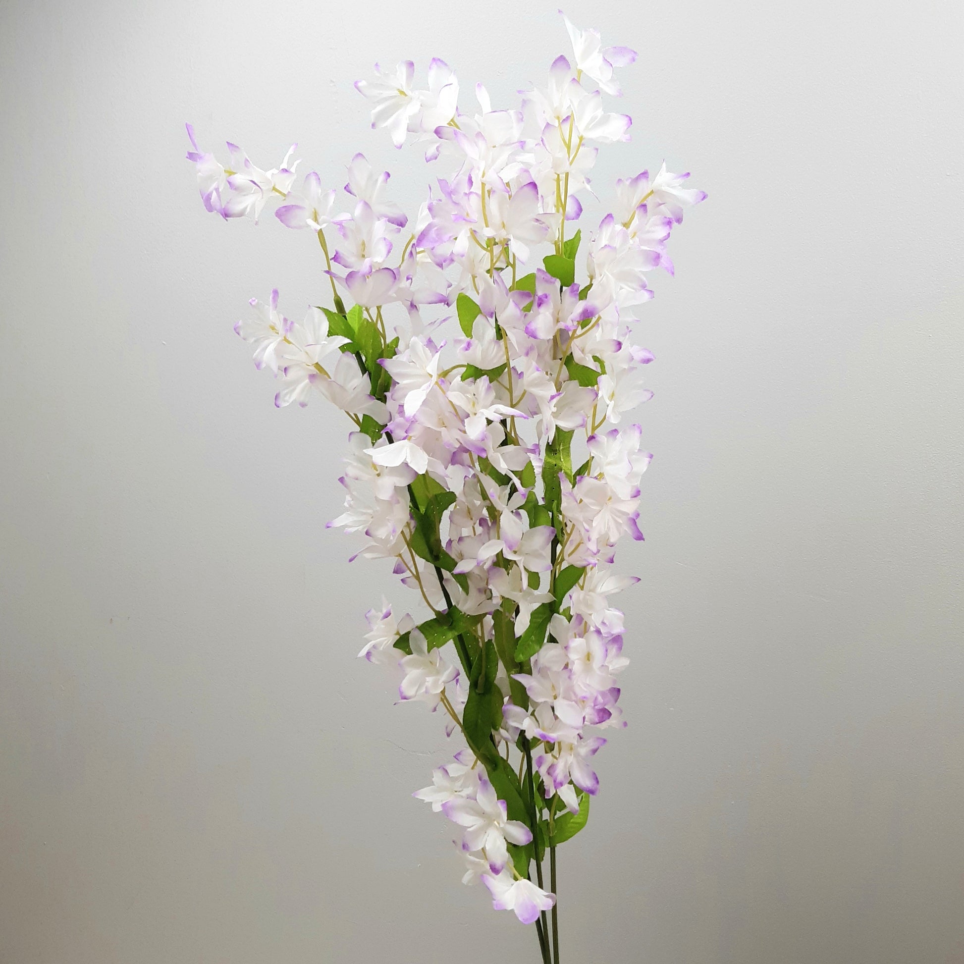 Artificial flower periwinkle spray bunch with white and purple flowers on a gray background