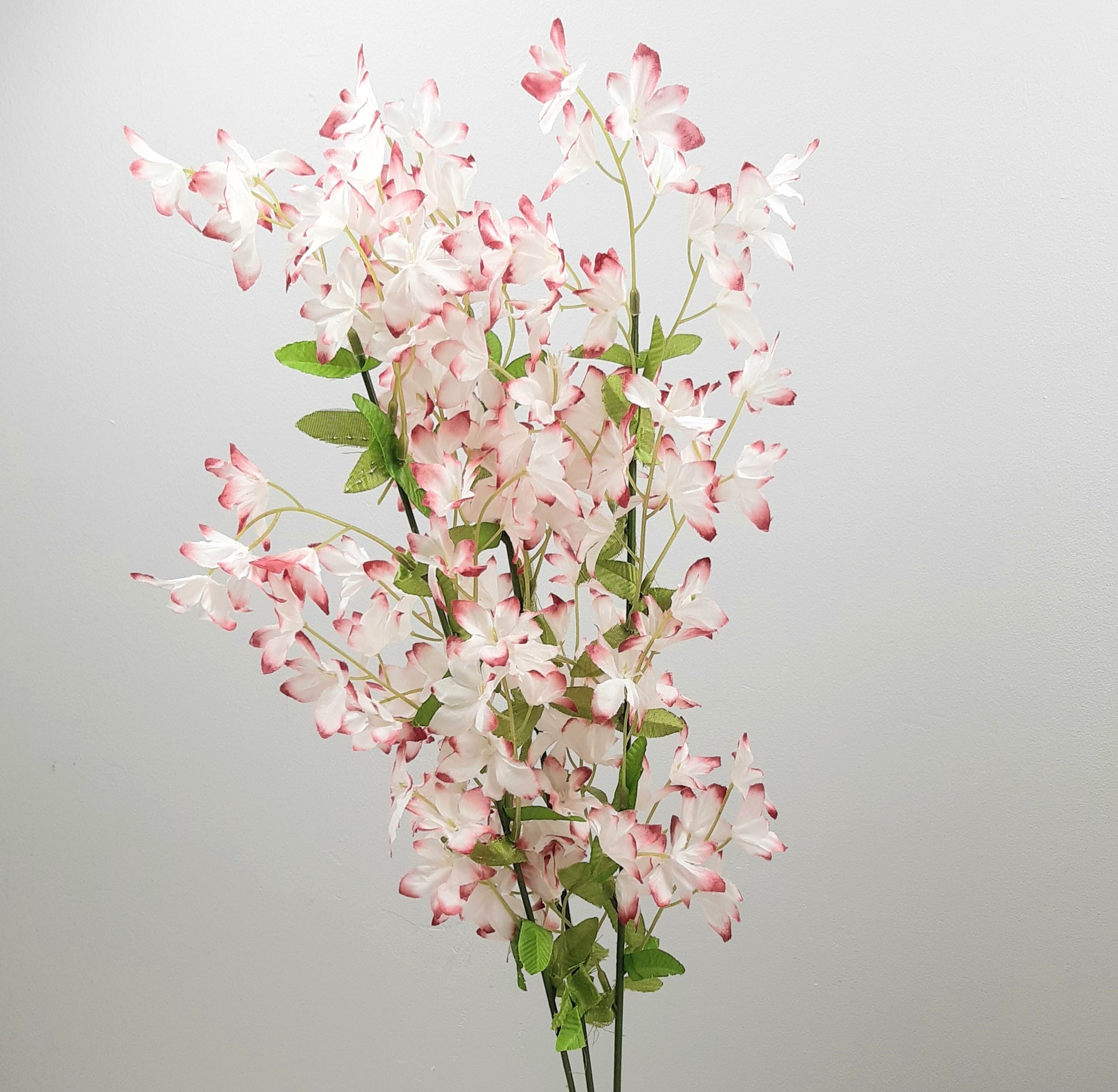Artificial flower periwinkle arrangement with pink and white blossoms on a gray background
