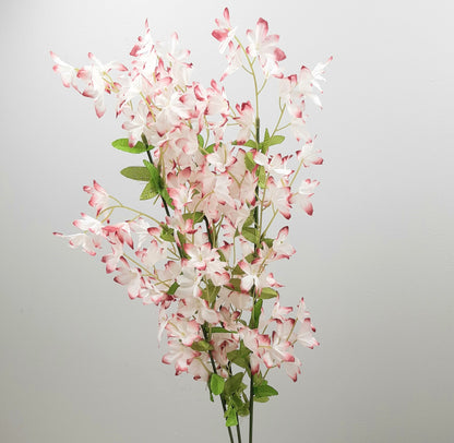 Artificial flower periwinkle arrangement with pink and white blossoms on a gray background
