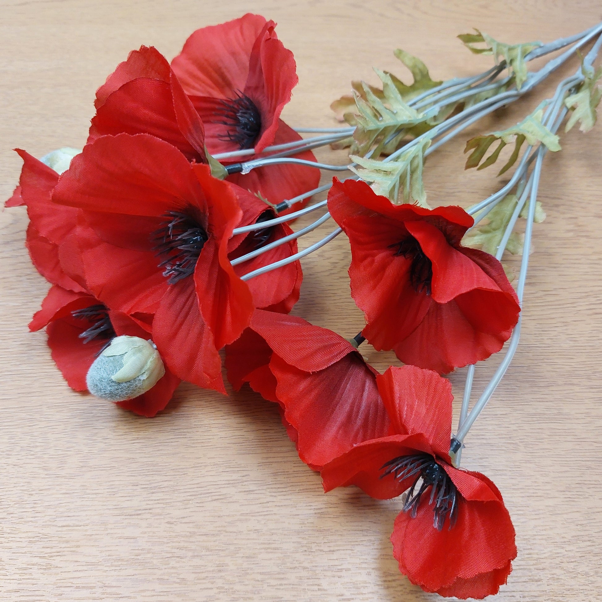 Bouquet of red artificial poppies on a wooden surface