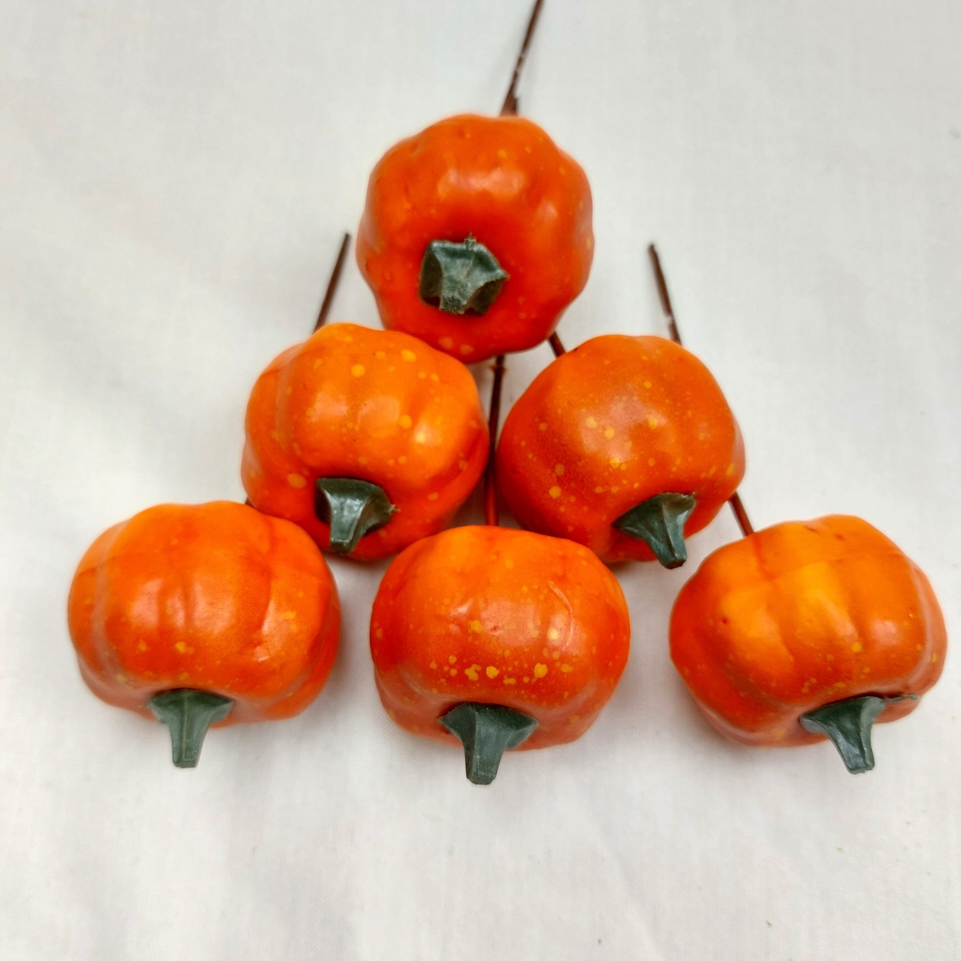 Faux Orange pumpkin picks with stems on a white background