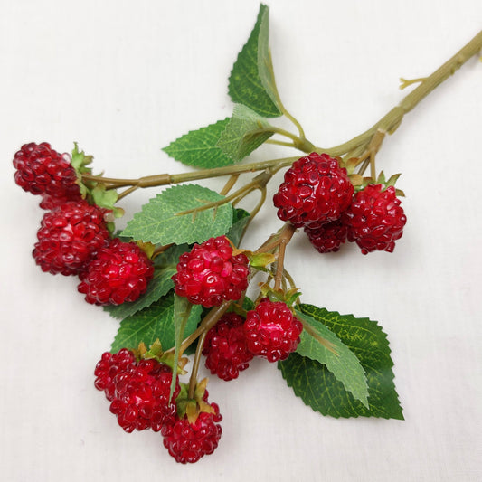 Artificial Red Raspberries with green leaves against a white background