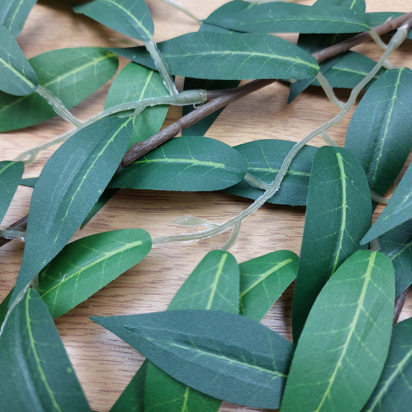 Close-up of green artificial Ruscus leaves on a wooden surface