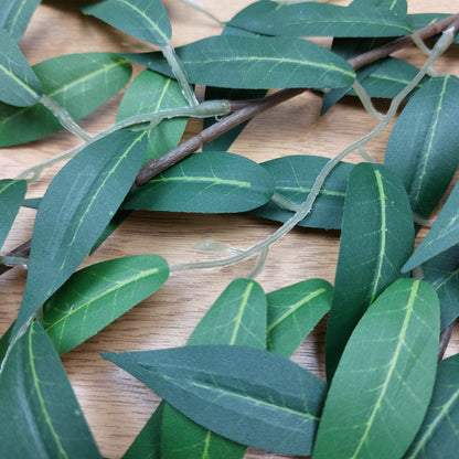 Close-up of green artificial Ruscus leaves on a wooden surface