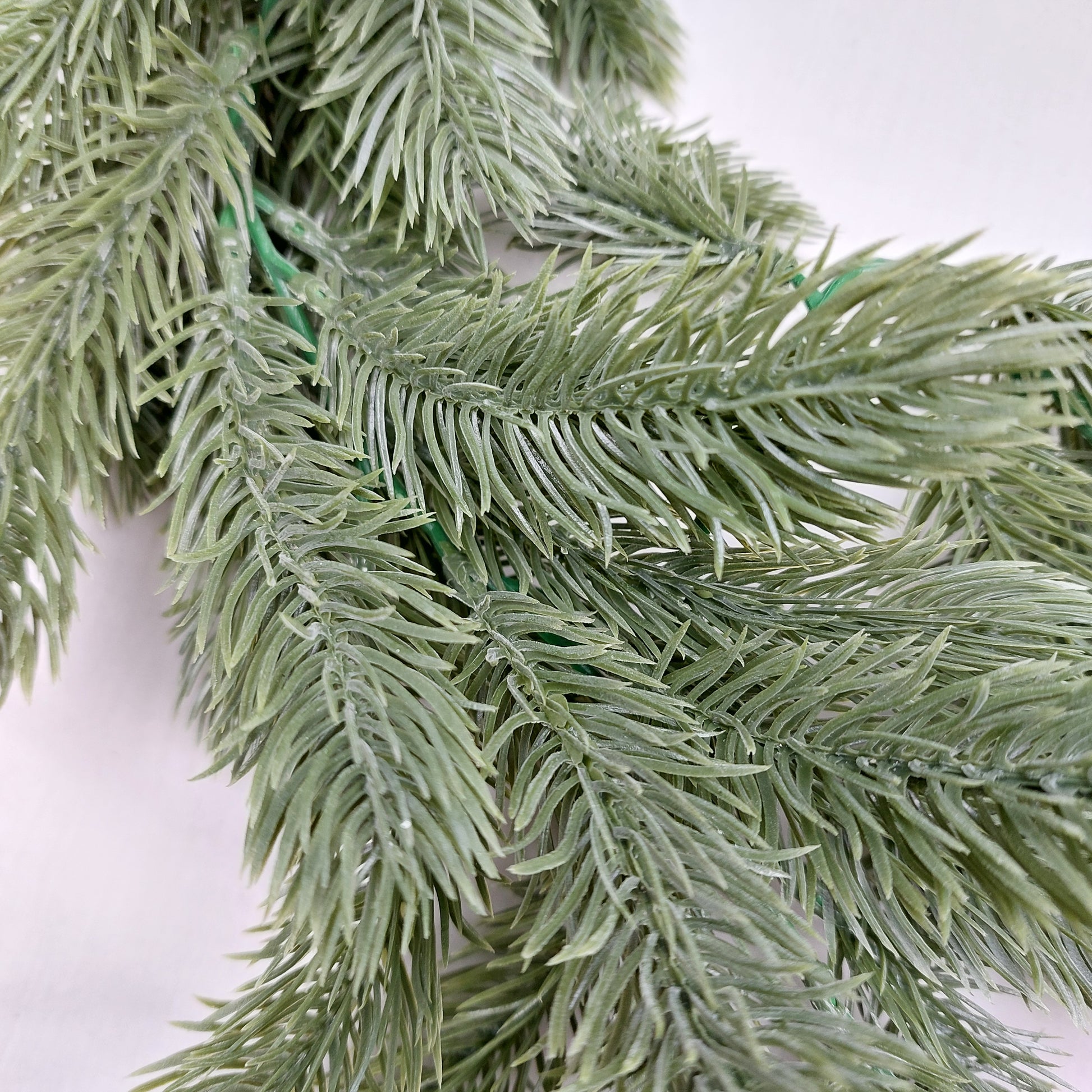 Close-up of artificial spruce greenery on a white background