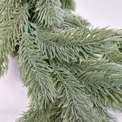 Close-up of artificial spruce greenery on a white background