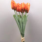 A bunch of artificial Orange Tulips against a pale background