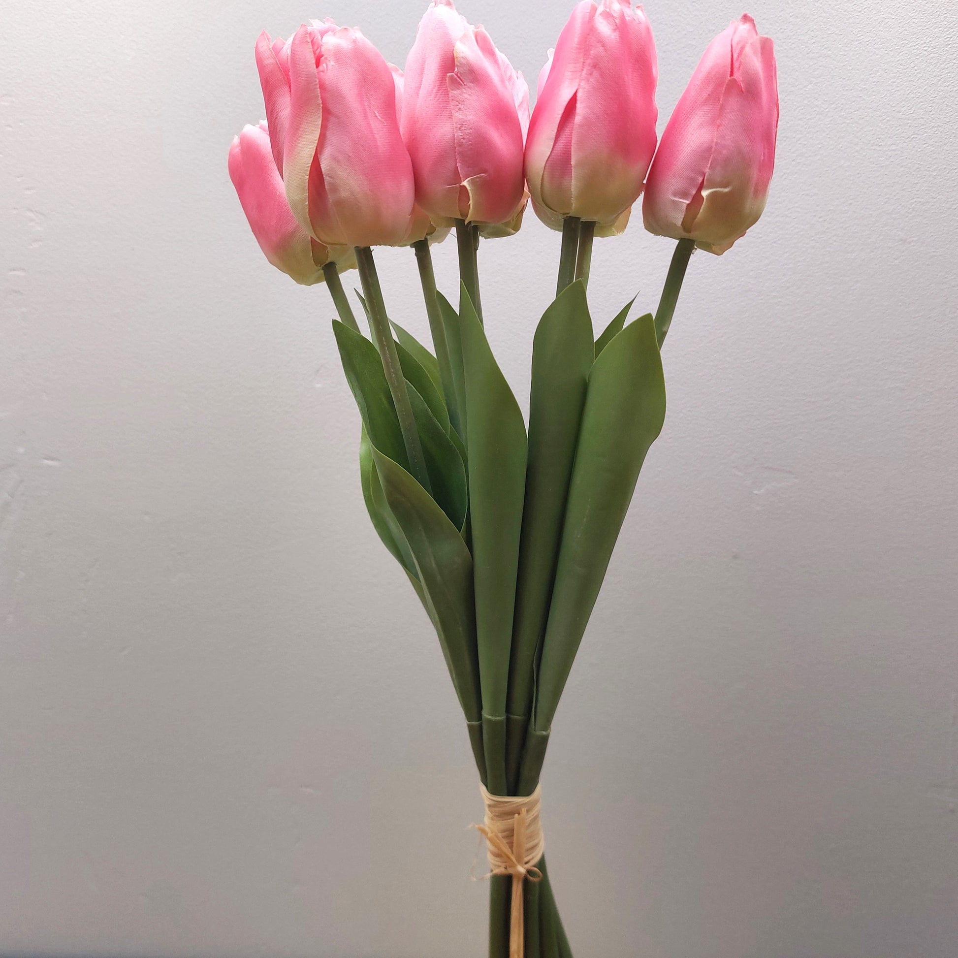 A bunch of artificial Pink Tulips against a pale background