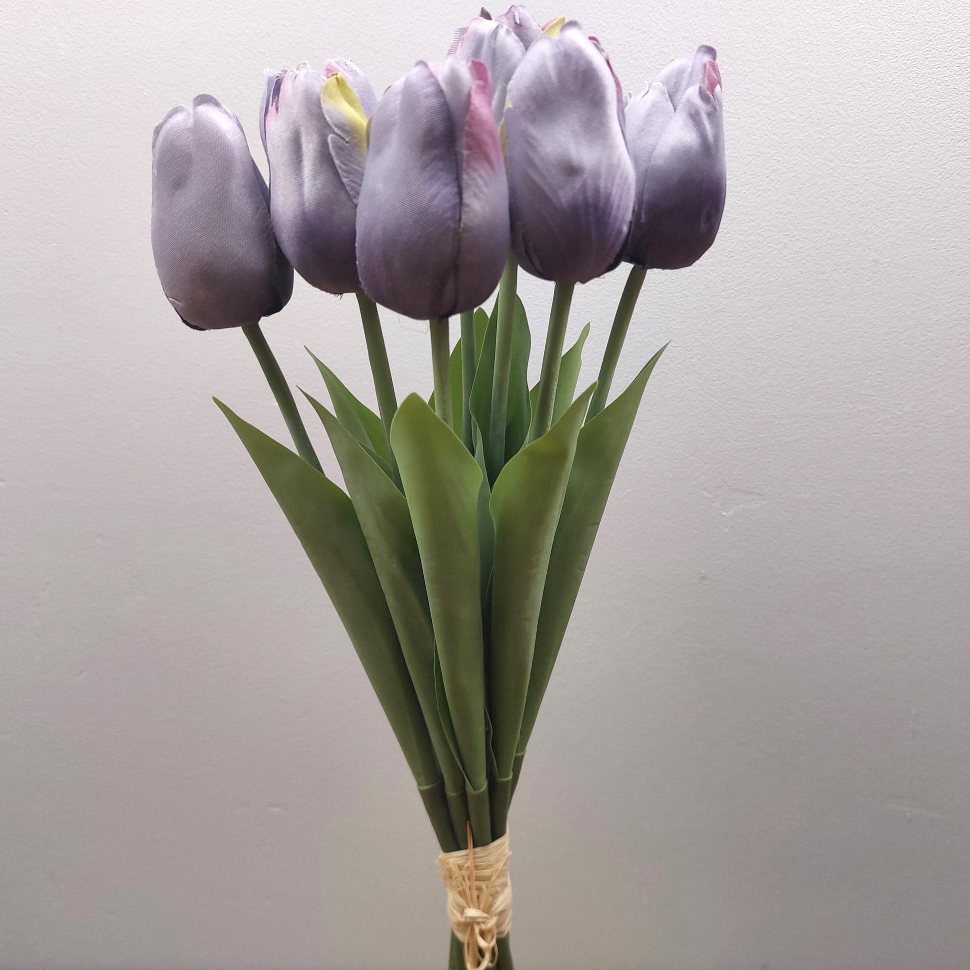 A bunch of artificial Purple Tulips against a pale background
