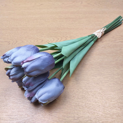 A bunch of artificial Purple Tulips laying down against a wooden background