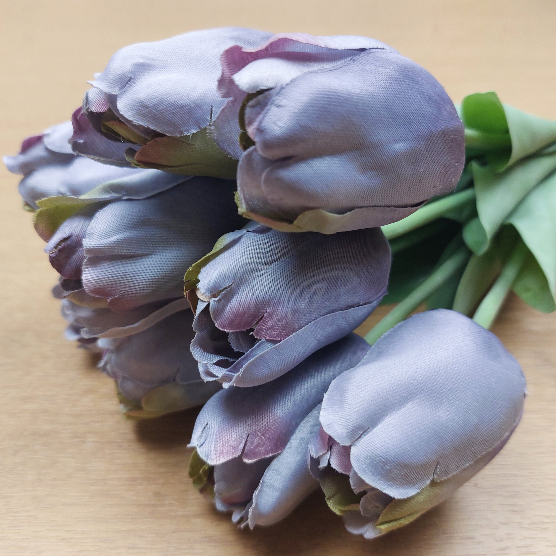 A close up of artificial Purple Tulips on a wooden background