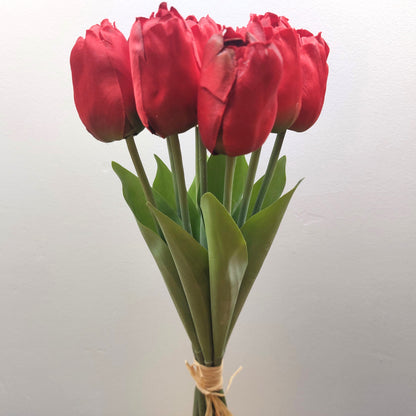 A bunch of Artificial Red Tulips against a pale background