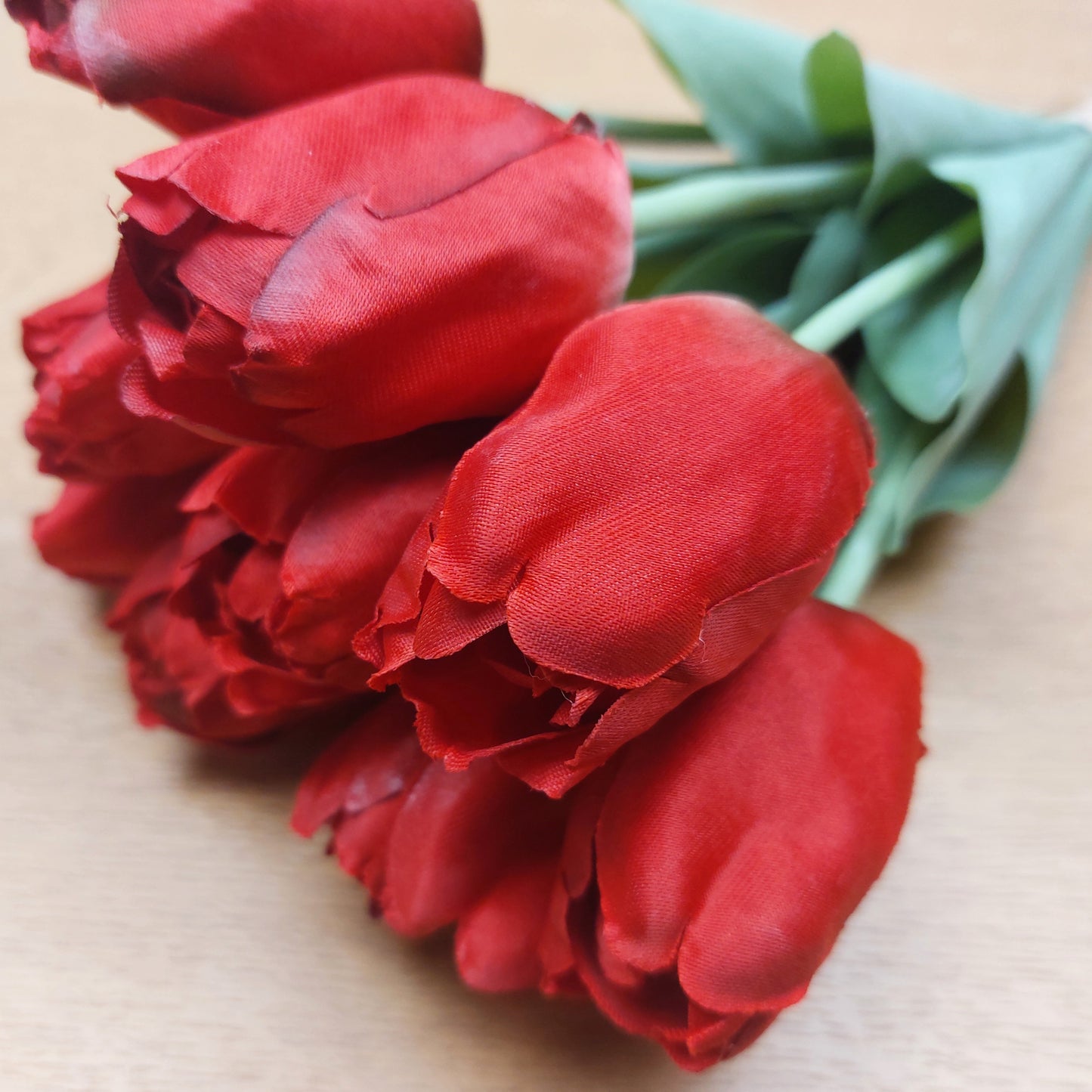 A close up of artificial Red Tulips against a wooden background
