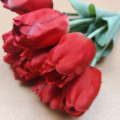 A close up of artificial Red Tulips against a wooden background
