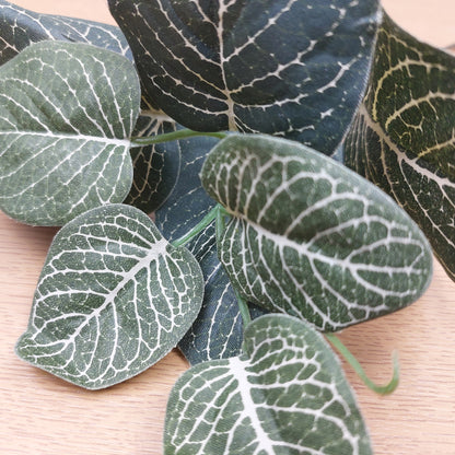 Close-up of artificial green leaves with white veins on a wooden surface