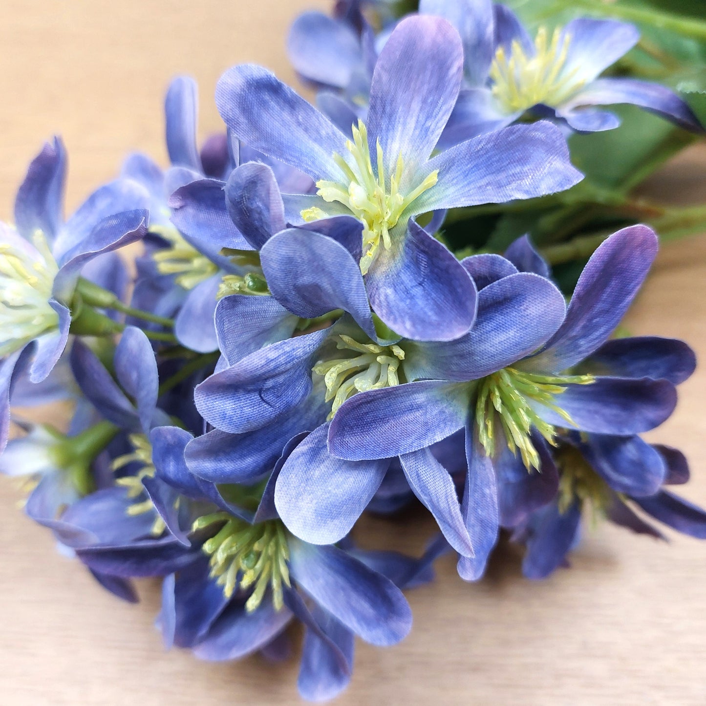 Close-up of artificial blue and purple flowers with green centers on a wooden surface