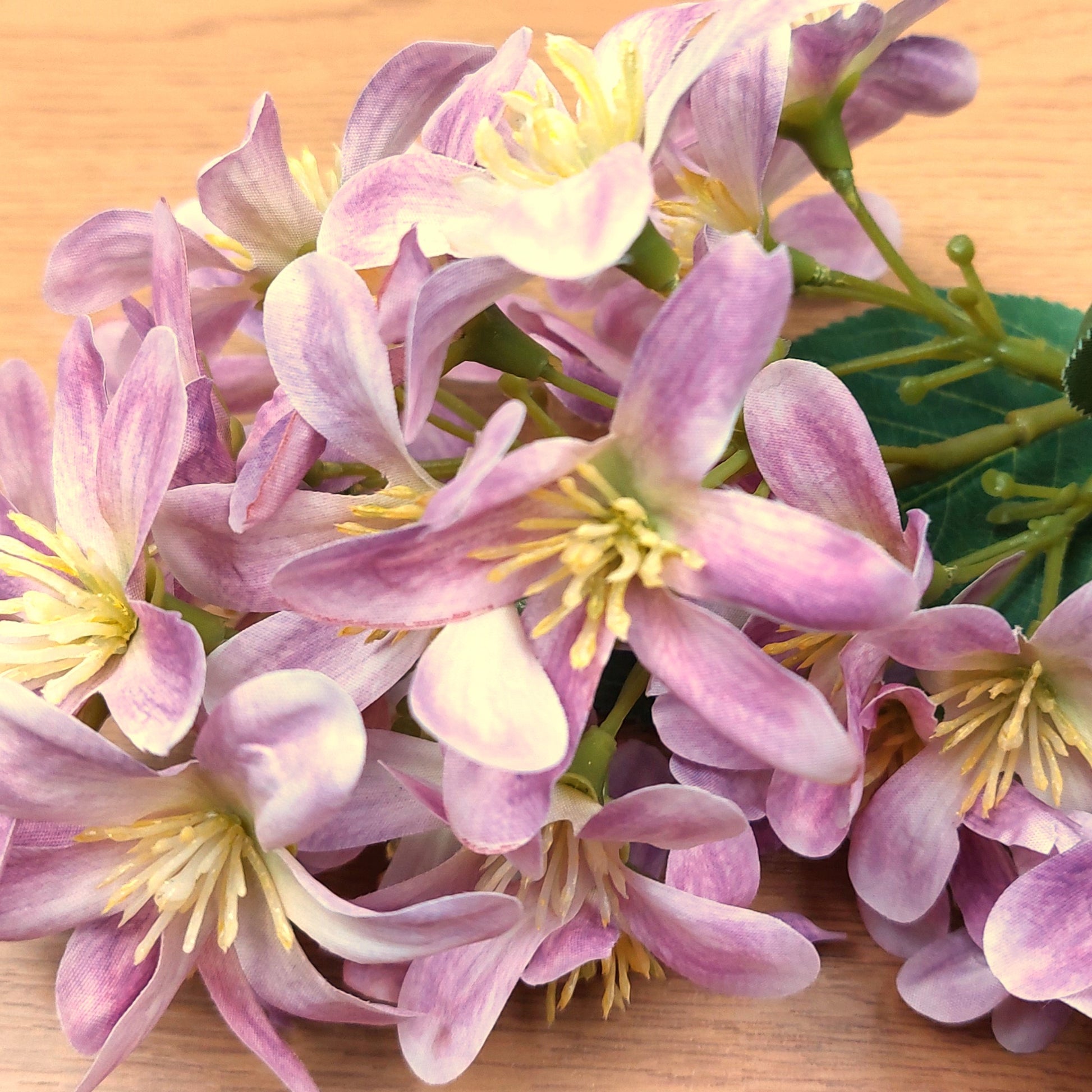 Close-up of artificial pink and yellow Vernicia Tung Blossom flowers on a wooden surface