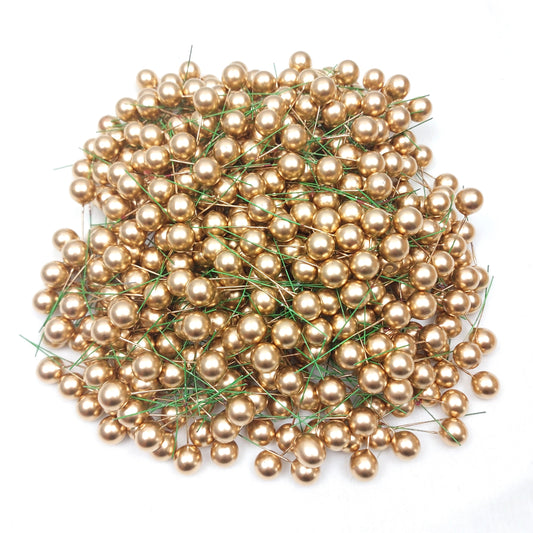 A large collection of faux wired gold berries on a white background