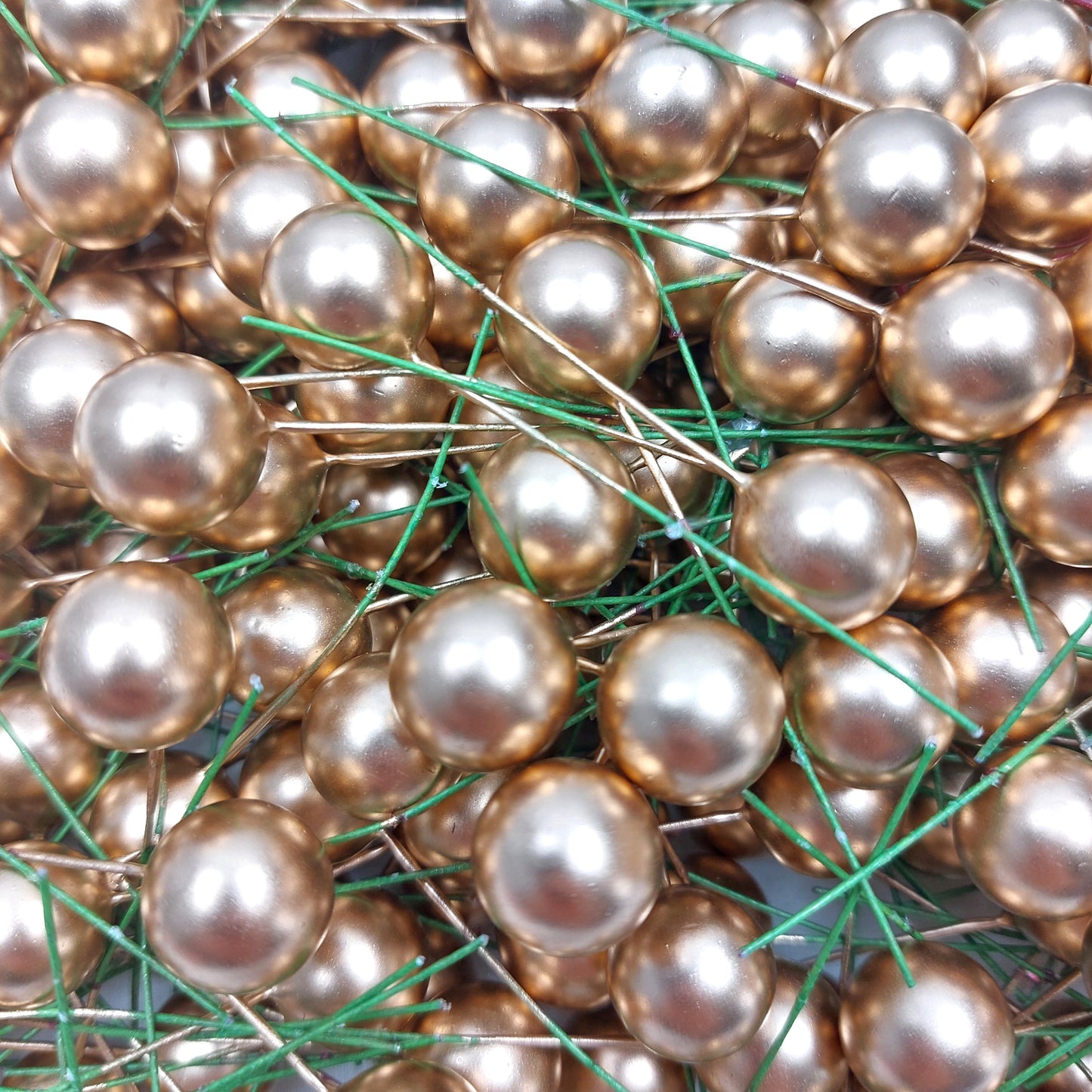 Close up of Gold artificial berries wired against a white background
