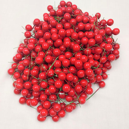 A large quantity of faux red berries on a white background