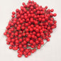 A large quantity of faux red berries on a white background
