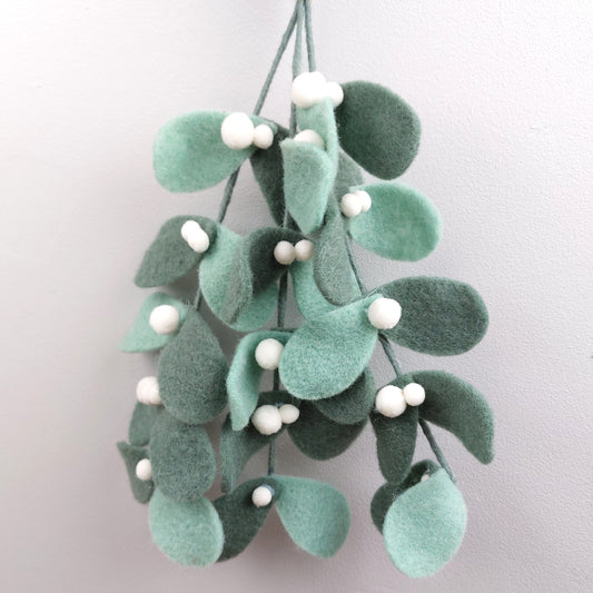 Decorative mistletoe felt hanging swag with green leaves and white berries on a light gray background