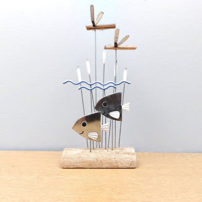 Decorative ornament with a fish design on a wooden base against a light gray background