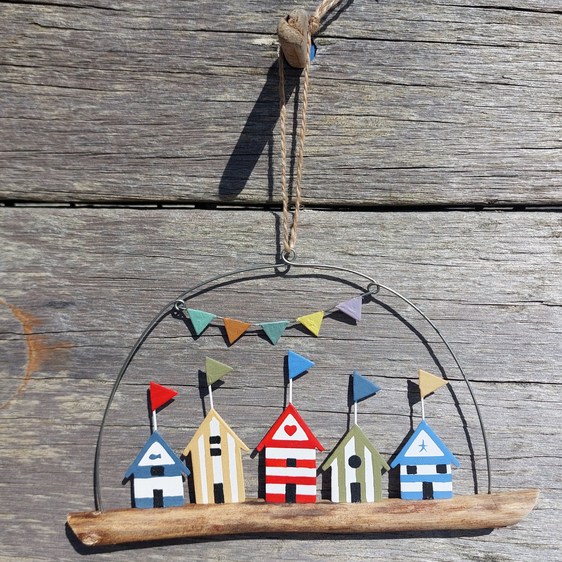 Decorative hanging with beach hut and flag bunting garland design on a wooden surface