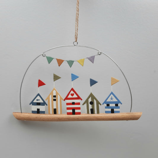 Hanging decoration with colorful beach huts and bunting on a plain background