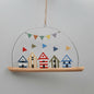 Hanging decoration with colorful beach huts and bunting on a plain background