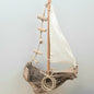 Decorative sailboat made from driftwood with a white sail on a light gray background