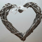 A hanging Grey Colour Wicker Heart with a white satin ribbon and bow.