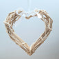 A hanging Natural Colour Wicker Heart with a white satin ribbon and bow.