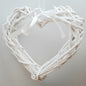 A hanging White Colour Wicker Heart with a white satin ribbon and bow.
