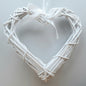 A hanging White Colour Wicker Heart with a white satin ribbon and bow.