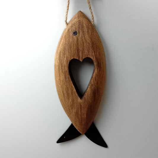 A brown wooden carved fish with metal fins and eye, with a heart shape carved in the middle hanging from a jute rope against a pale background.