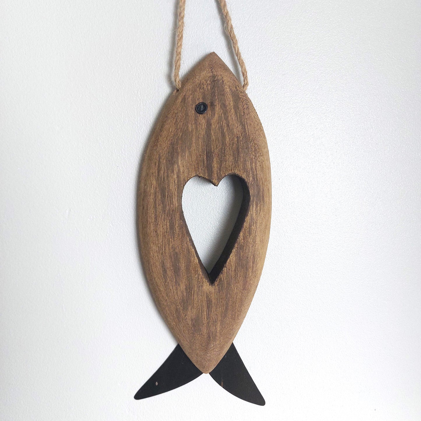 Wooden rustic style fish-shaped ornament with a heart cutout on a white background