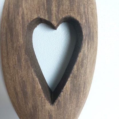 Wooden hanging ornament with a cut out heart shape inside on a white background