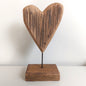 Wooden heart-shaped sculpture on a stand against a white background