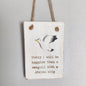A whitewashed style wooden plaque, showing a seagull with the phrase "Today I will be happier than a seagull with a stolen chip" hanging from a jute string against a pale background.