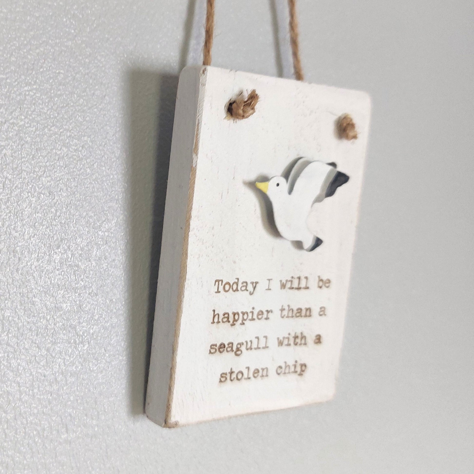 Wooden whitewashed sign with a seagull illustration and humorous text on a white background