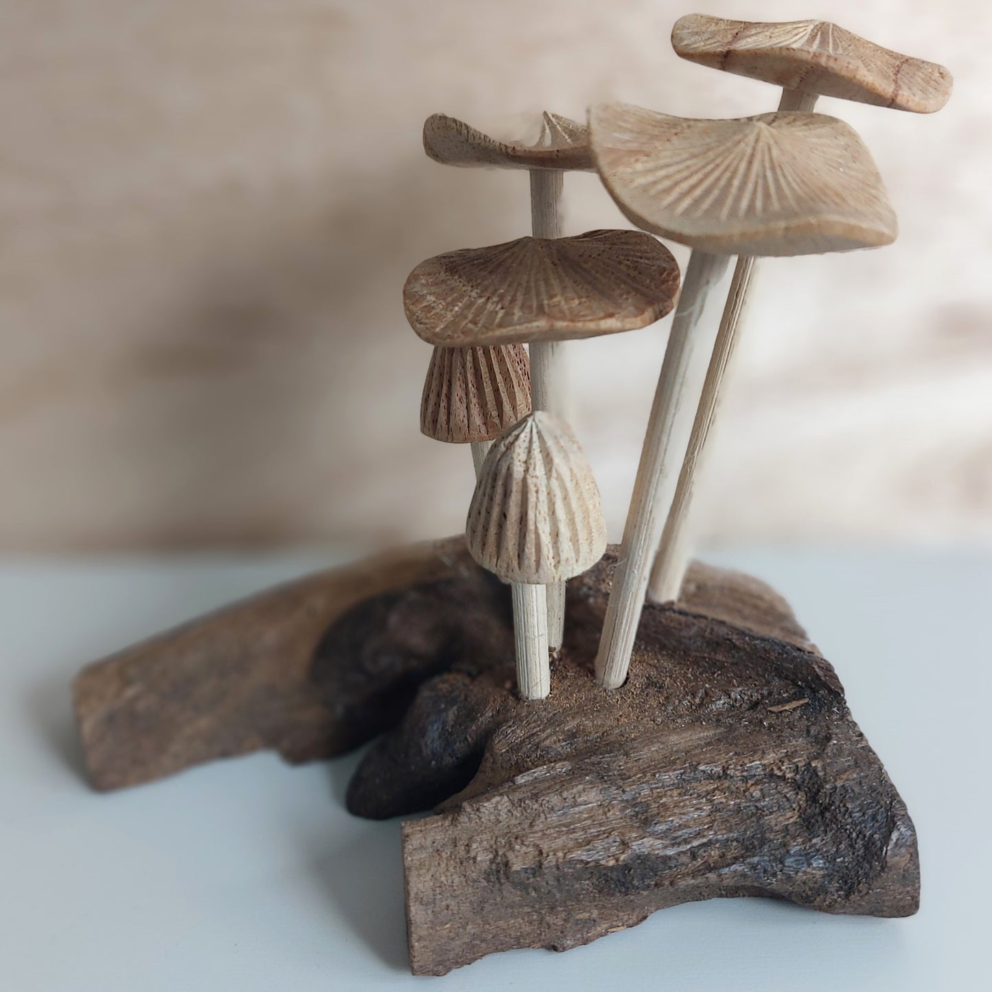 Handmade Wooden mushroom figurines on a piece of driftwood with a blurred background