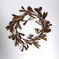 An ornate metal red/brown bronze leafy mistletoe wreath against a plain background
