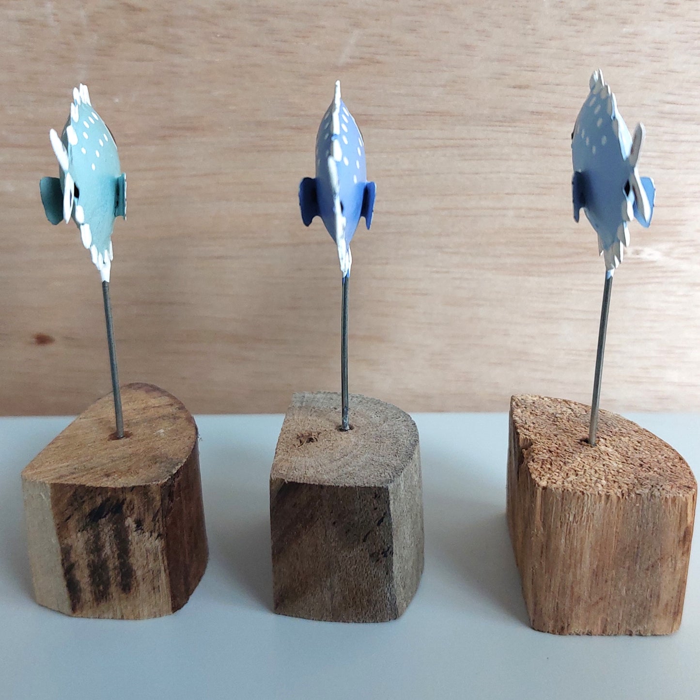 Three wooden stands with decorative blue and white puffer fish facing away on a light wood background