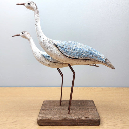 Decorative wooden wading birds sculpture on a wooden base against a light gray background