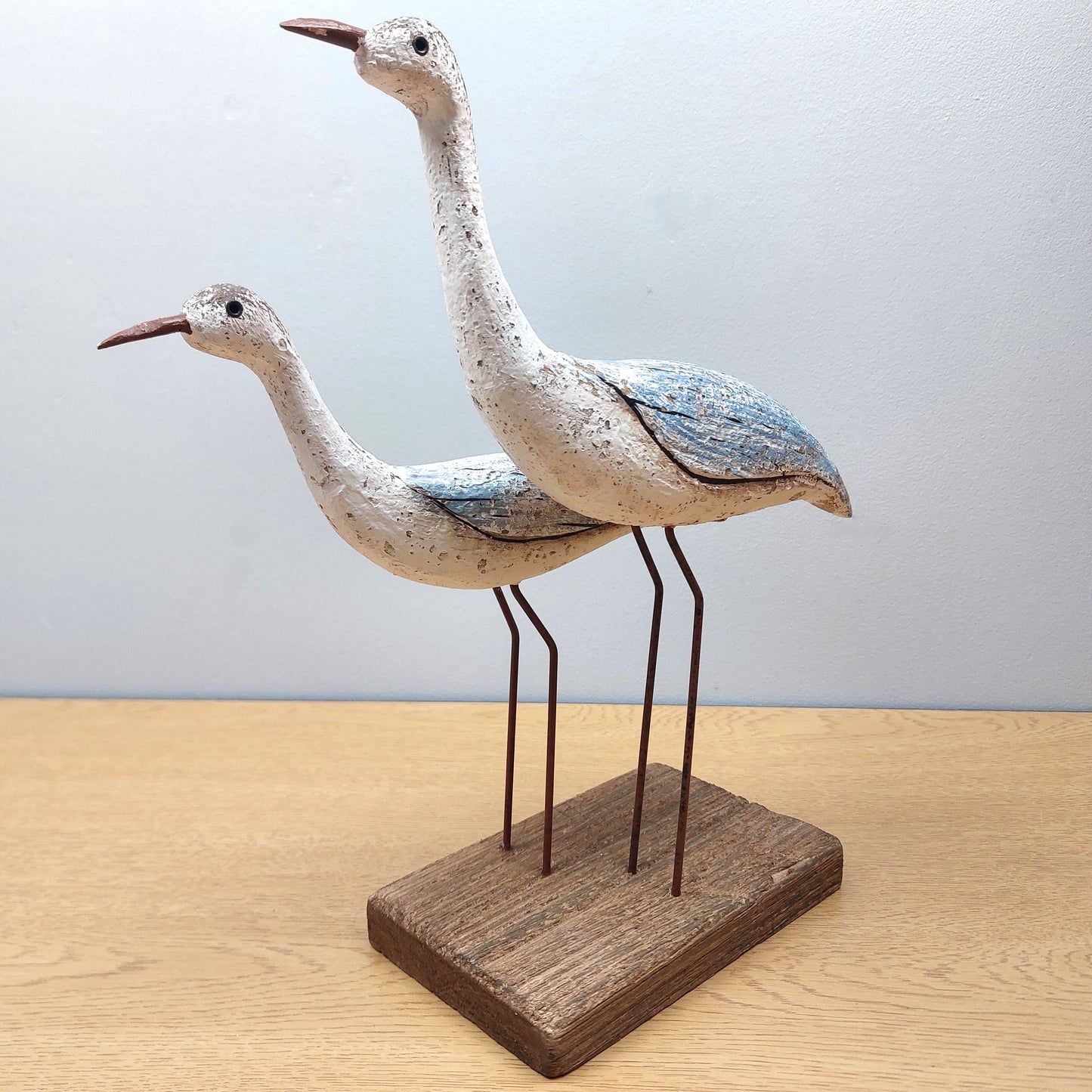 Two wooden wading birds on a wooden base against a light background