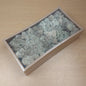 A rectangular box filled with pale Sage and Cream Finland Reindeer moss, photographed from above on a light wood tabletop.