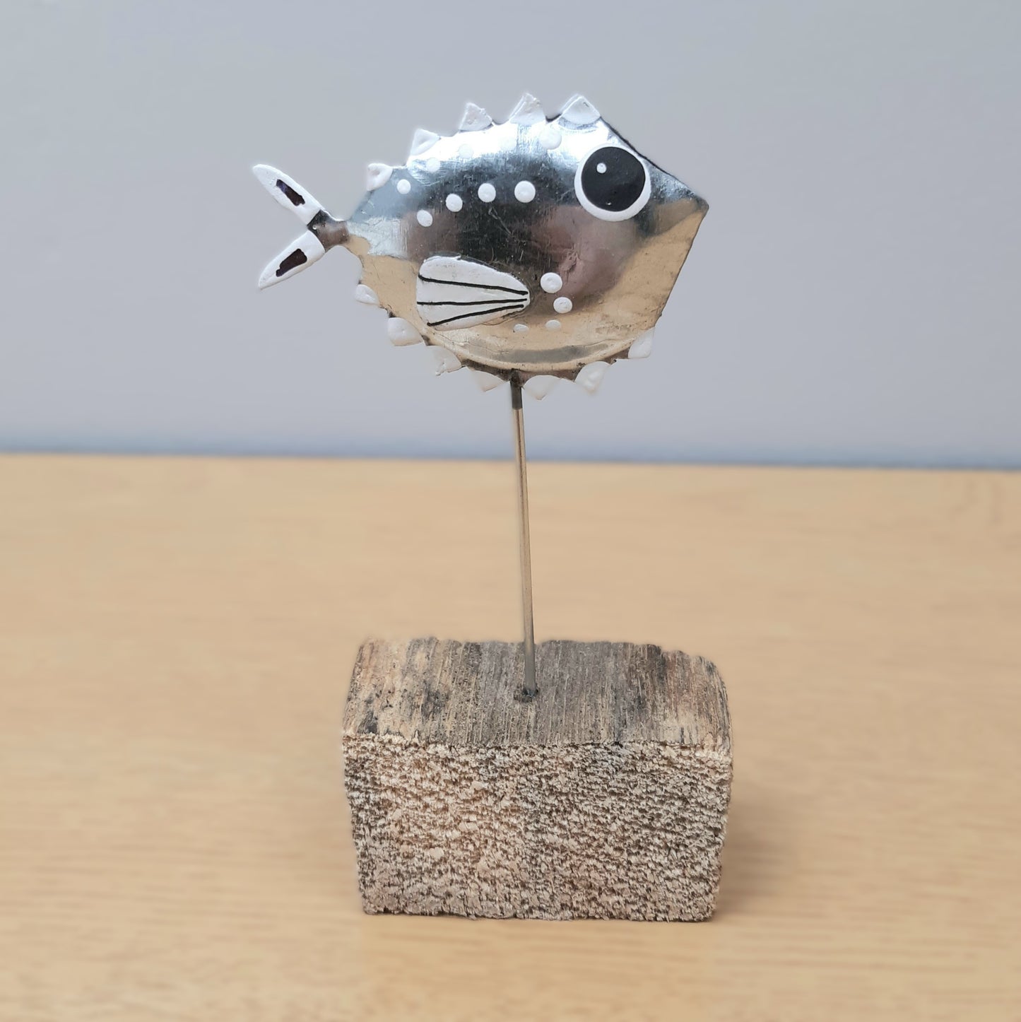 Decorative fish on a stick in a wooden block against a plain background