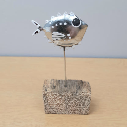 Decorative fish on a stick in a wooden block against a plain background