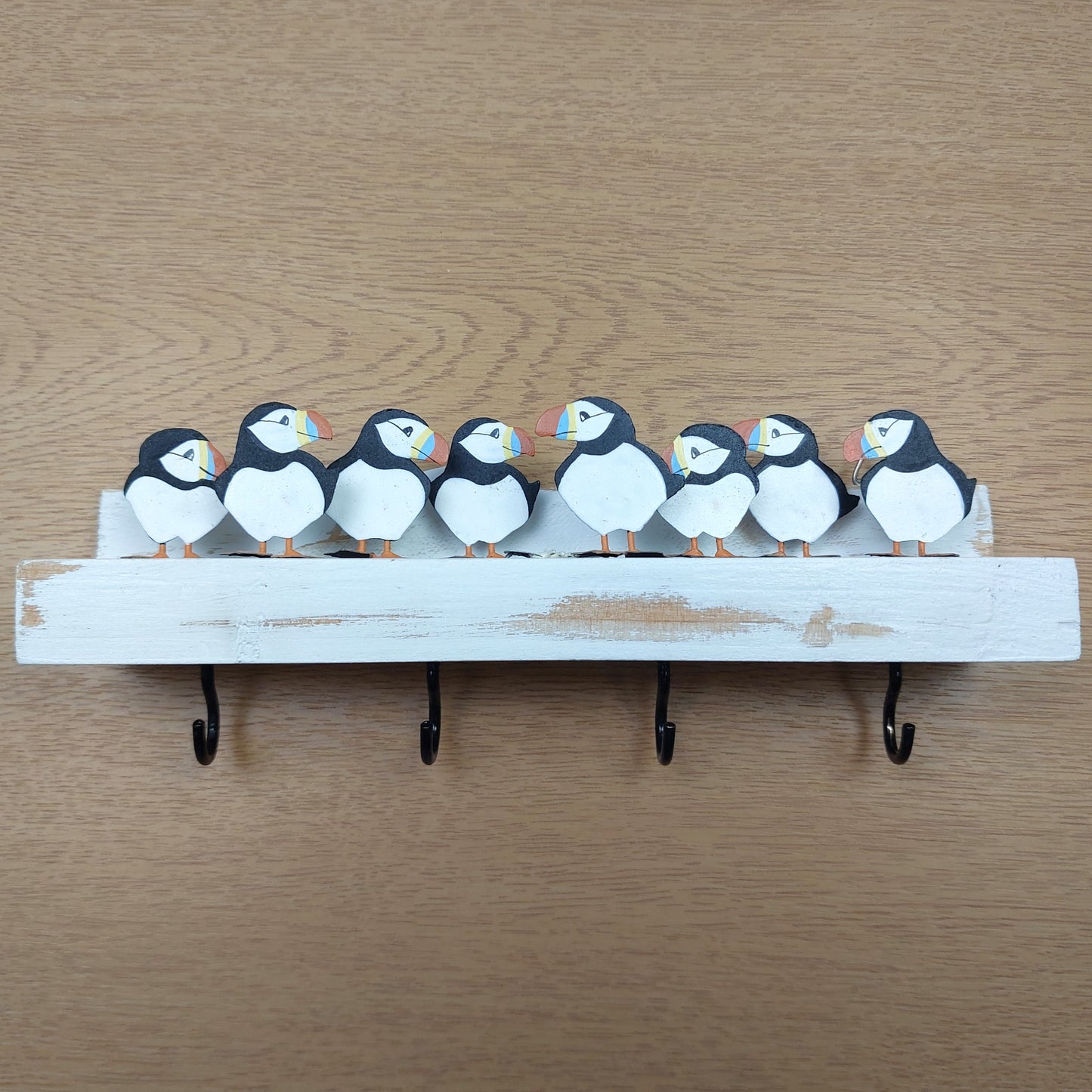 Decorative key holder with puffin designs on a wooden background